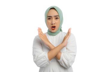 Angry young Asian woman in green hijab and white blouse with crossed arms, showing stop or rejection gesture isolated on transparent background