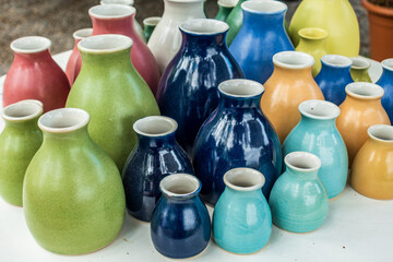 Collection of handmade ceramic vases in various colors and sizes displayed on a table at an artisan market