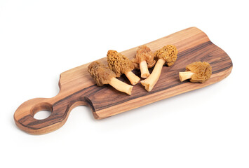 Five Fresh Morel Mushrooms (Morchella esculenta) on Wooden Cutting Board Isolated on White