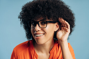 Curious young African American woman wearing glasses and dental braces listening carefully