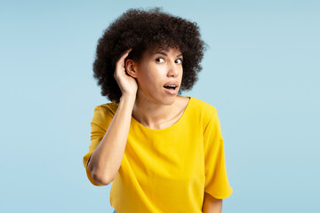 Curious young woman holding hand to ear trying to hear conversation