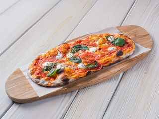 Classic Margherita pizza with a thin, crispy crust, rich tomato sauce, melted mozzarella, and fresh basil leaves. Served on a rustic wooden board with a warm, textured background, emphasizing its