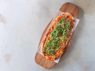 Classic Margherita pizza with a thin, crispy crust, rich tomato sauce, melted mozzarella, and fresh basil leaves. Served on a rustic wooden board with a warm, textured background, emphasizing its
