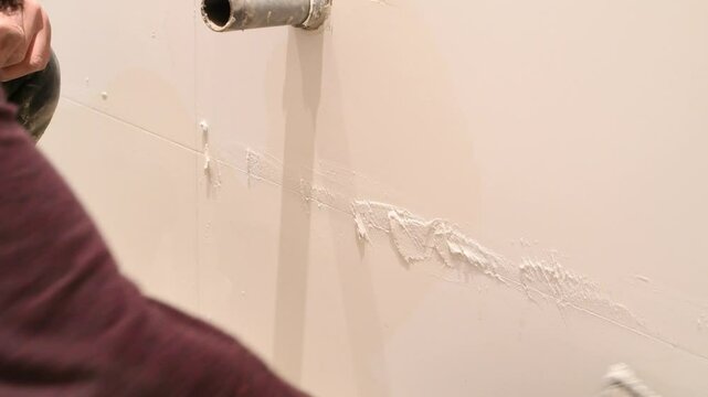 Construction worker carefully grouting white ceramic tiles demonstrating precise tiling technique and craftsmanship during bathroom renovation project