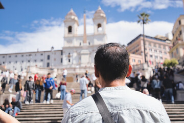 Middle aged male tourist in a light gray shirt and black shoulder bag enjoying the sunny view of...