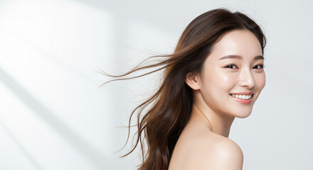 髪を風になびかせ振り向く若い女性（美容、ビューティー、化粧品、、スキンケア、健康）