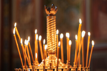 burning candles in the temple, wax candles lit against the background of a cross with a crucifix, the concept of christian religion, prayers for the salvation of the soul