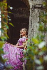 Beautiful girl with long hair braided in a braid, in corset and magnificent pink dress.