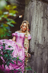 Beautiful girl with long hair braided in a braid, in corset and magnificent pink dress.
