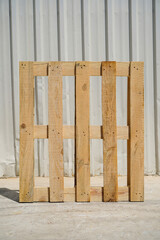 Wooden Pallet Leaning Against a Metal Wall in Industrial Setting
