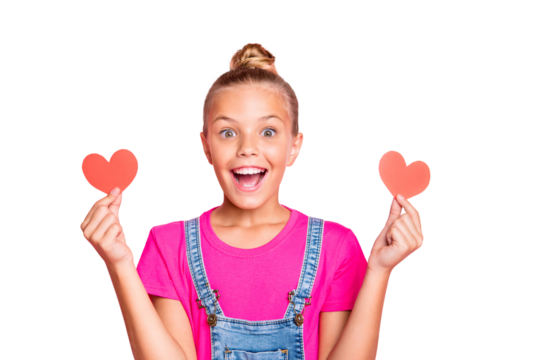 Photo of excited cheerful cute nice schoolgirl holding two hear shapes red with her hands wearing jeans denim overall fuchsia t-shirt isolated over pink pastel color background - Powered by Adobe