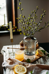 A steaming glass teapot sits on a table, surrounded by fresh lemon halves and a jar of...