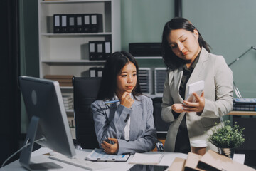Asian Businesswoman Using laptop computer and working at office with calculator document on desk, doing planning analyzing the financial report, business plan investment, finance analysis concept.