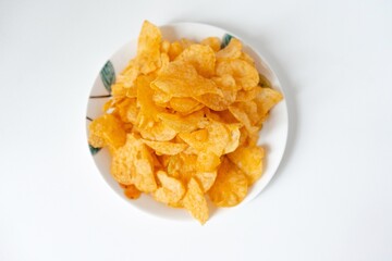 A pile of puffed potato chips snacks on a white painted plate