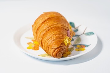 A beef and cheese croissant on a Chinese white painted plate, white background