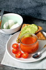 Still life of fresh cheese with gazpacho and avocado toast