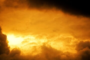 Fototapeta premium Dramatic clouds gather at sunset, their soft peaks illuminated by the fading light of day.