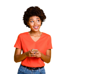 Copyspace photo of cheerful curly wavy trendy woman holding telephone with her hands wearing jeans denim orange t-shirt standing pensively looking up isolated over yellow vivid color background