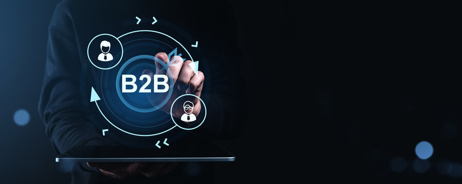 Businessman using touch interface to activate B2B digital network with creative icons and futuristic technology graphics on dark blue background.