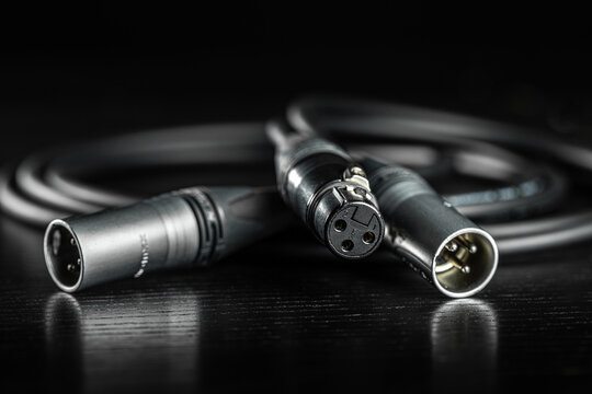 Xlr connectors and audio cable lying on a dark wooden surface
