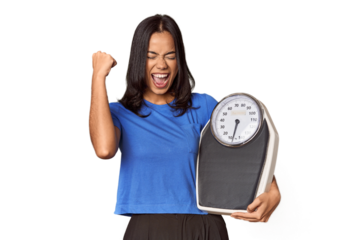 Filipino woman with scale in studio raising fist after a victory, winner concept.