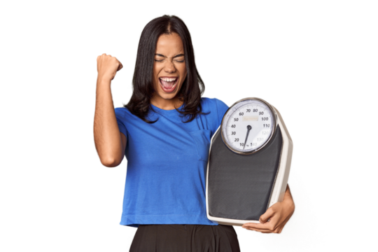 Filipino woman with scale in studio raising fist after a victory, winner concept.