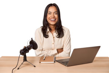 Woman records podcast with laptop laughing and having fun.