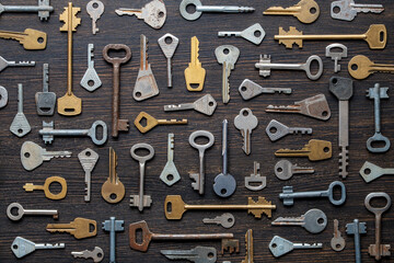 Obraz premium Set of different old keys on wooden background, top view, closeup. Safety and security concept. Pattern of many keys