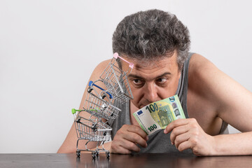 Conceptual story about poverty with a grey-haired middle-aged man, 100 euro bill and miniature...