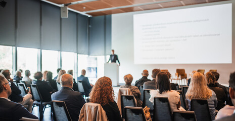 Speaker giving a talk in conference hall at business event. Rear view of unrecognizable people in...