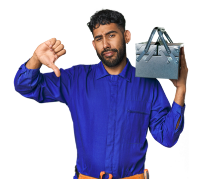 Hispanic worker with toolbox in studio showing a dislike gesture, thumbs down. Disagreement concept.