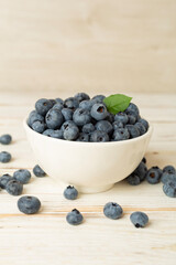Bowl with fresh blueberries on wooden table