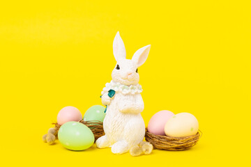 Easter bunny with painted eggs on color background
