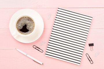 Notebook with cup of coffee on wooden background, top view