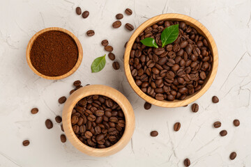Roasted coffee beans with leaves on concrete background,top view