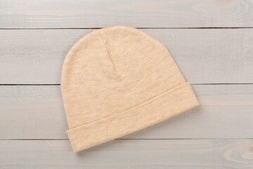 Stylish beanie hat on wooden background, top view