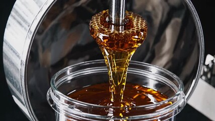Golden honey pouring in slow motion with spectacular amber transparency