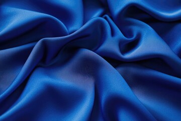 Obraz premium Close-up of luxurious, deep blue silk fabric with soft, flowing folds and elegant texture.