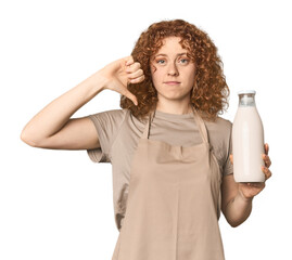Young Caucasian redhead woman with milk showing a dislike gesture, thumbs down. Disagreement...