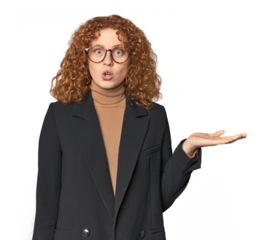 Young Caucasian redhead in business attire impressed holding copy space on palm.