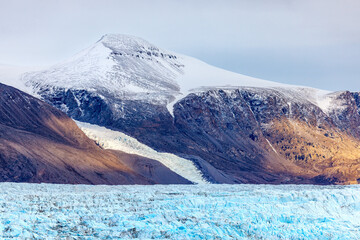 Closeup of the terminus of the Nunatak glacier, which means lonely mountain in Inuit, in Geologfjord, Northeast Greenland National Park, with sunlit snow covered mountains in the background. © Rixie
