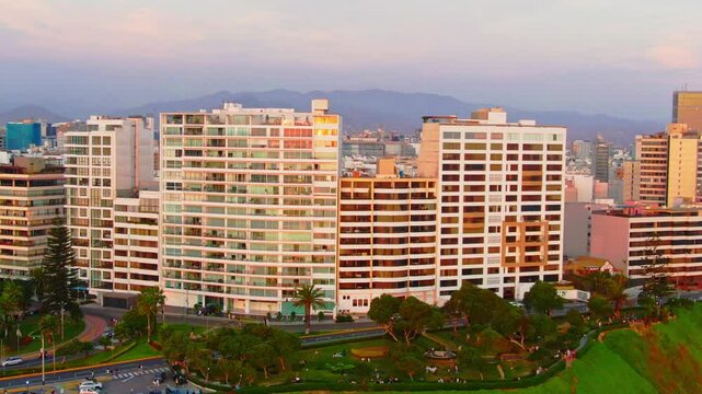 Aerial: Club Terrazas building at sunset with Bajada Balta and Malecon de Miraflores in the coast of Lima, Peru, orbit drone shot