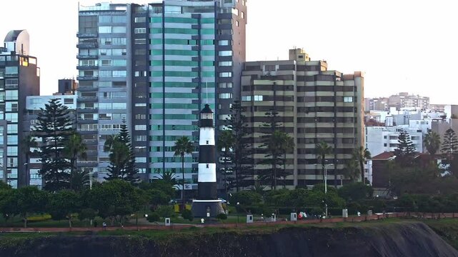 Orbit drone shot of La Marina Lighthouse and Itzhak Rabin Park at sunrise in Malecon de Miraflores in the coast of Lima, Peru