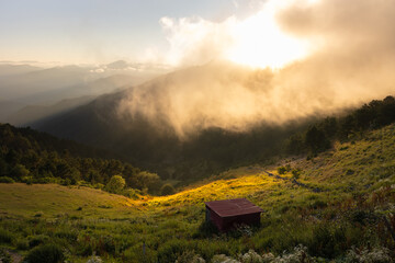 Landscape of the mountain range and forest covered hills with fog at sunset