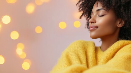 Fototapeta premium A young woman with curly hair sits comfortably in a bright yellow sweater, eyes closed, enjoying a calm moment surrounded by soft lights