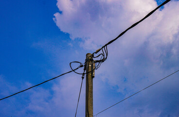 Electricity poles with hanging cables, under a clear sky, create a typical rural or urban scene.