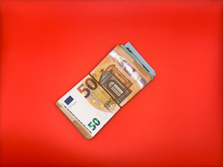 A pile of euro cash tied with a rubber band in the center of the image, top view