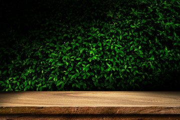 empty wooden table top on dark green Leaves texture , bar in a dark background, for your photo montage or product display, Space for placing items on the table.	