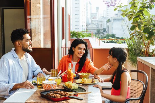 Latin American family enjoying an outdoor meal on a sunny day in the city - Powered by Adobe