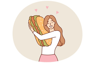 Happy woman hugging giant hamburger missing fast food after long diet to maintain slim figure